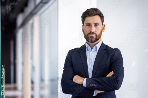 Portrait of serious self-confident male lawyer standing in office, crossed arms on chest and looking at camera photo