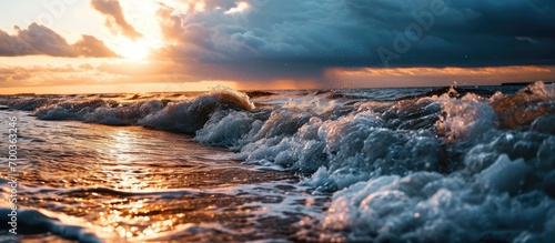 Stormy weather and captivating sunset over Baltic Sea in Latvia. Close-up shot of waves. Majestic spring scenery with indications of cyclone and climate change.