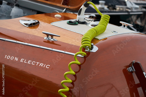 the wooden side of the modern electric elegance motor boat in port of Hercules in Monaco, green electric cable for charging batteries, sunny glare of the sun, glossy surfaces shine in sunny weather