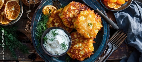 Potato pancakes with garnishes, including sour cream, dill, applesauce, and dried orange slices. photo