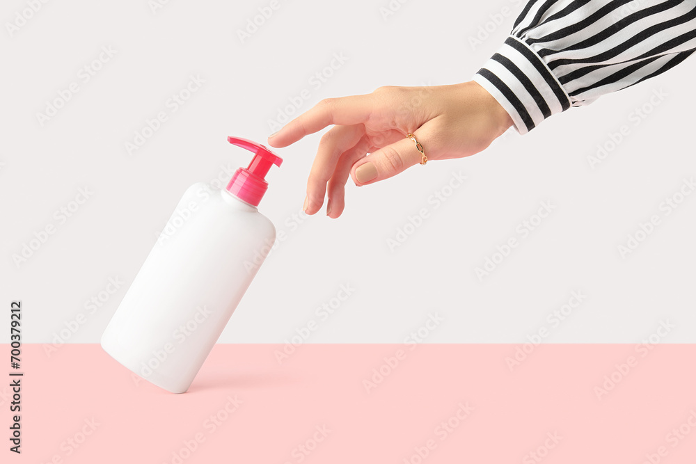 Womans hand touch white bottle on pastel pink and white background. Self care concept Womans hand touch white bottle on pastel pink and white background. Self care concept