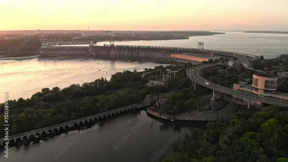 A panoramic view of a river hydroelectric power plant at sunset, showcasing the serene flow of water, the architectural marvel of the plant, and the enchanting play of lights as day turns into night. A panoramic view of a river hydroelectric power plant at sunset, showcasing the serene flow of water, the architectural marvel of the plant, and the enchanting play of lights as day turns into night.