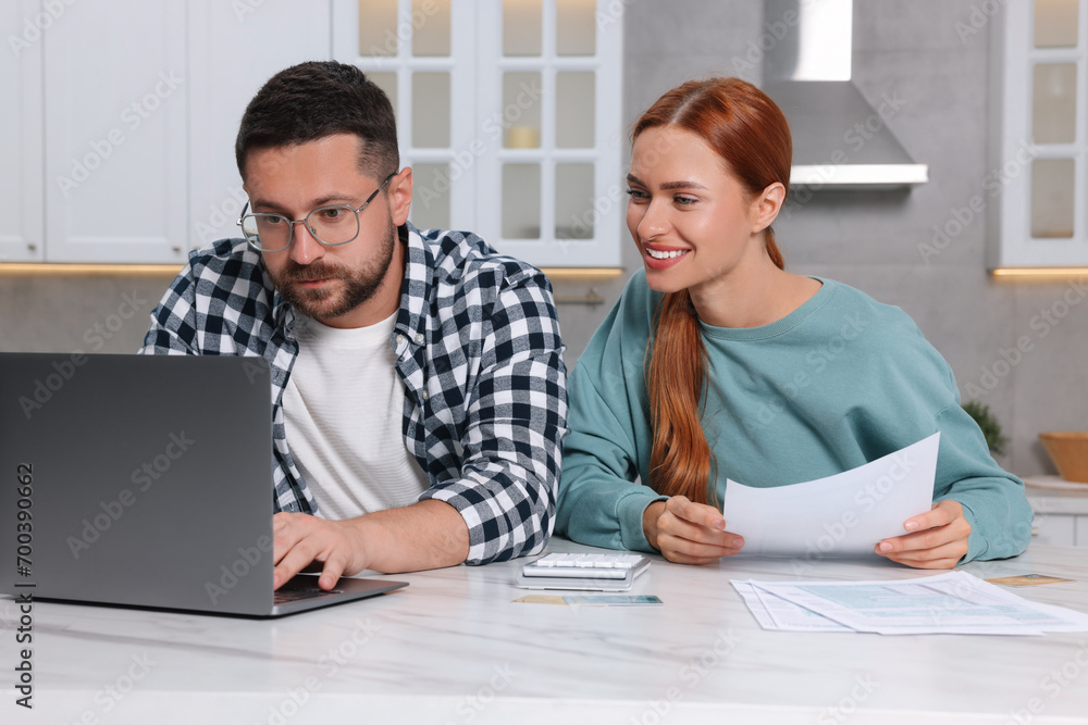 Couple using laptop for paying taxes at home Couple using laptop for paying taxes at home