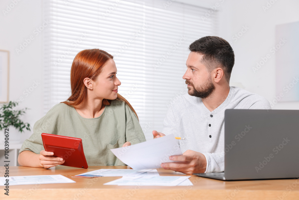 Couple calculating taxes at table in room Couple calculating taxes at table in room