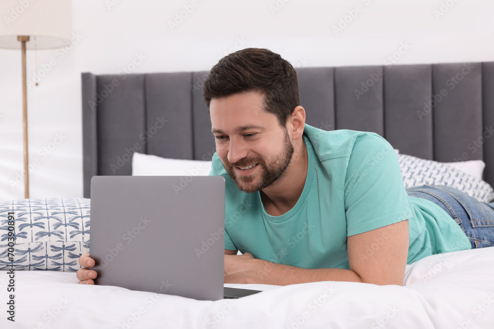 Happy man having video chat via laptop in bedroom Happy man having video chat via laptop in bedroom