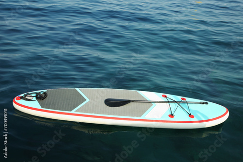 One SUP board with paddle on water in sea, space for text