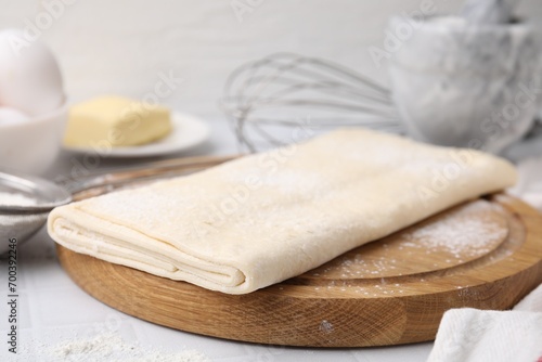 Raw puff pastry dough on white tiled table, closeup