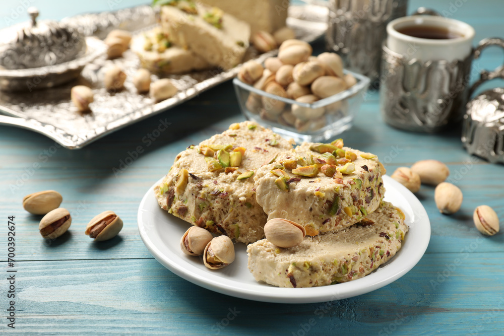 Tasty halva with pistachios served on light blue wooden table