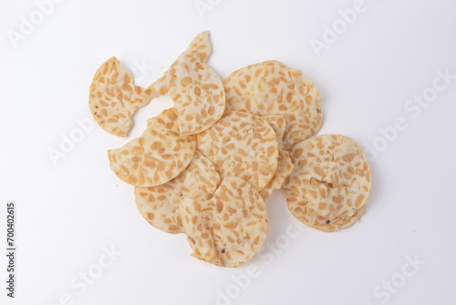 Keripik Tempe or Tempeh Chips are made from soybeans and served on a wooden plate. Isolated on white background. usually used as souvenirs