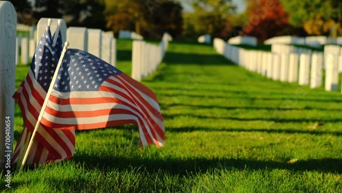 Field of American flags at Sunset. Flags on grave stones for memorial day remembrance at a cemetery. Small American flags and headstones at National cemetary- Memorial Day display. photo