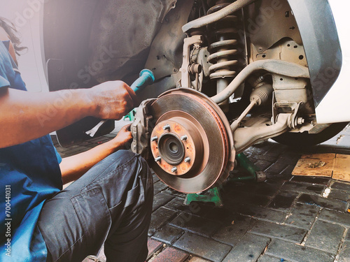 A mechanic change brake pads and system check in basic maintenance. Hands a technician man repairing action and service disk brake for car. photo