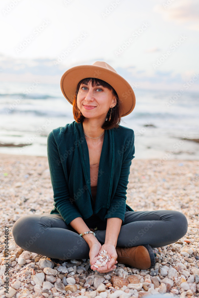 Portrait of a young smiling girl in a hat, sitting on the beach..Beautiful natural beauty woman smiling and laughing, posing for the camera on the beach.