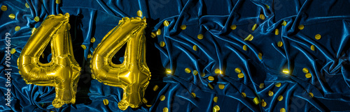 number forty four, gold foil balloon number on a blue velvet background with confetti. Birthday greeting card, inscription 44. Anniversary event. Banner. Stylish gold numeral, bright shiny. photo