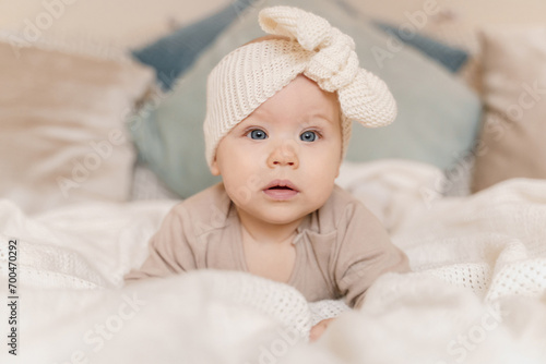 Cute little girl with a knitted bandage on her head lies on the bed photo
