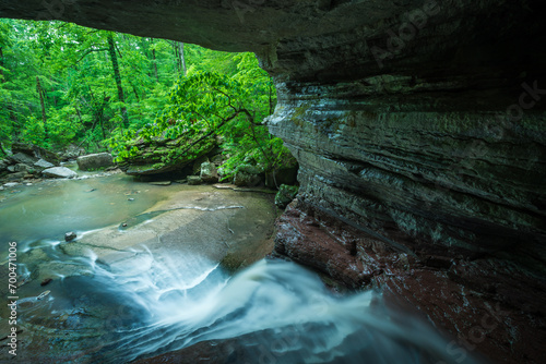 Stream flowing through a cave into the forest photo