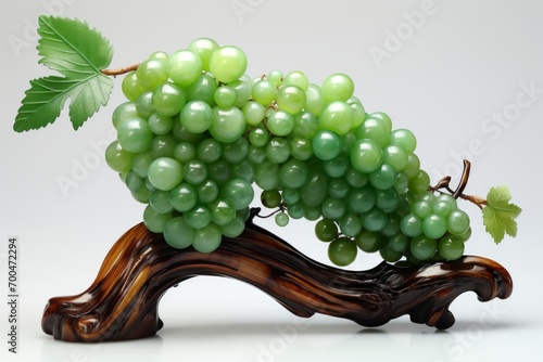 The beautiful art work of grape fruits with leaves made of green jade which is placed on the shining wooden base.