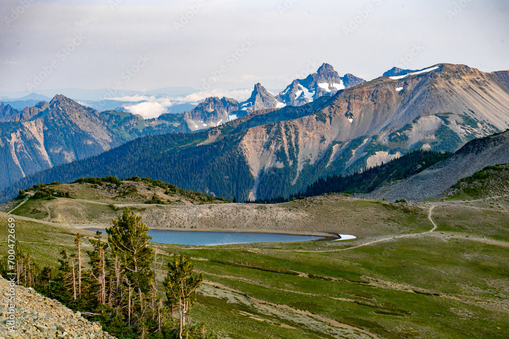 Open alpine meadow with a lake backed by jagged rocky mountains - Mount Rainier National Park