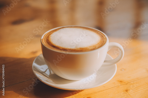 Coffee in white cup on wooden table, with spoon.