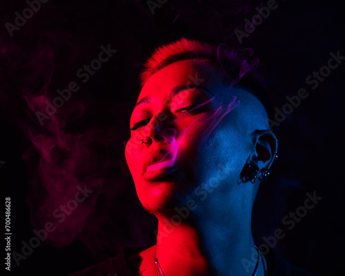 Close up portrait of asian woman with short hair smoking in neon light. 