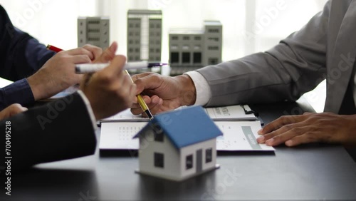 Businessman is negotiating a contract for the purchase and sale of a house. Real estate agent is offering a house for sale and a businessman signs an agreement document. photo