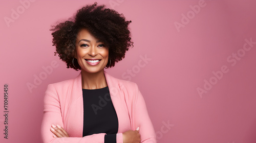 Portrait of a beautiful smiling middle aged black woman in a pink business suit on a pink studio background with copy space. concept of valentine's day, cosmetics, cosmetology and femininity.