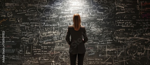 Businesswoman draws arrows consists of business doodles on blackboard Back view woman with safety helmet and marker pen in hands Idea generation and business development Coaching and mentoring