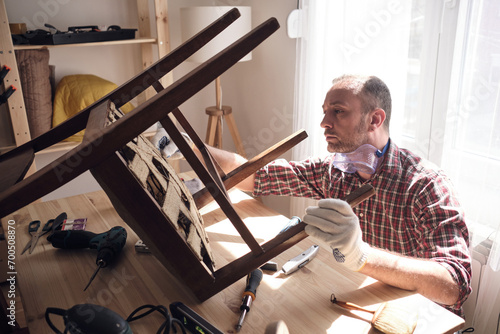 Obraz na plátně Man working in a small home workshop for furniture repairing and restoration