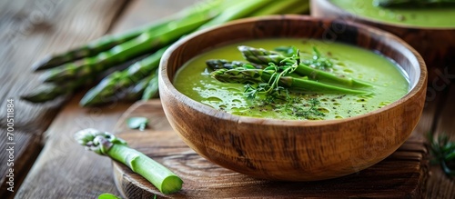 Fresh green asparagus soup in bowl on wooden table. Creative Banner. Copyspace image