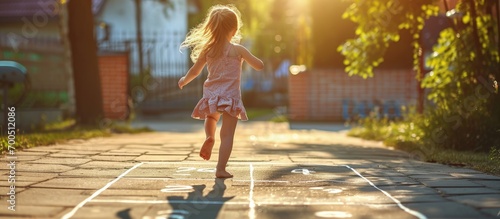 Closeup of little girl s legs and hop scotch drawn on asphalt Child playing hopscotch game on playground outdoors on a sunny day Summer activities for children. Creative Banner. Copyspace image photo