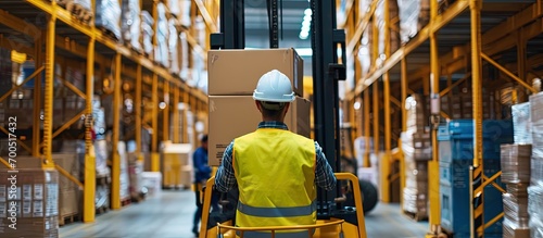 Custom warehouse Man customs officer and boxes Guy in yellow vest with her back to camera Tiered racks and forklift blurred Customs warehouse with cardboard boxes Career storage worker photo