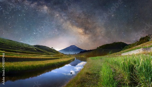mountain and rive field with river in the middle at night time, beautiful view of rice field at night time with miky way view above the mountain