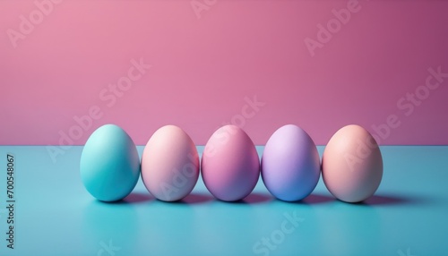  a row of pastel colored eggs sitting in a row on a blue surface against a pink and blue background with a pink wall in the middle of the background.