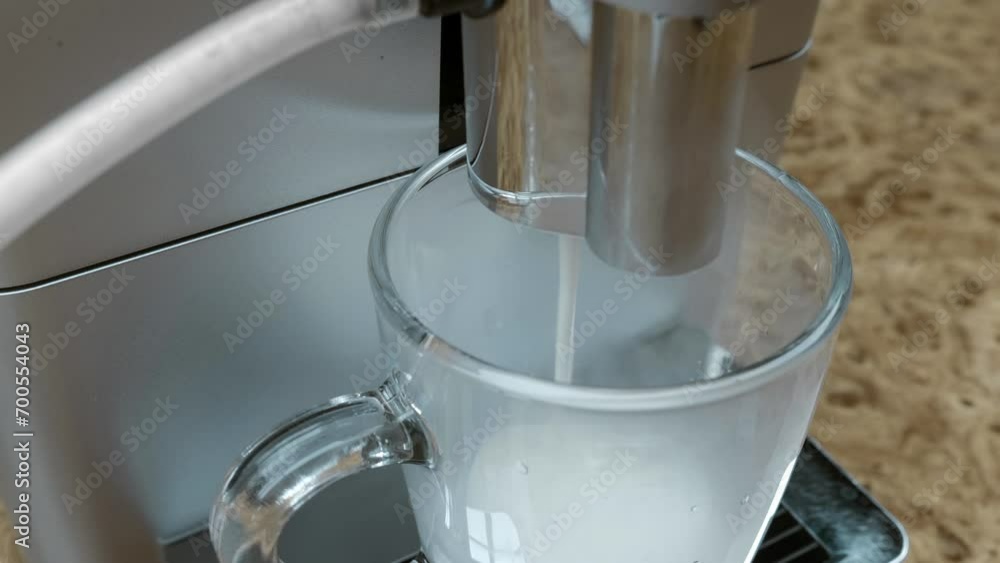 The coffee machine prepares an invigorating morning cappuccino, first frothing the milk and then pouring strong coffee from freshly ground aromatic Arabica beans. Closeup. Macro. Shot in motion The coffee machine prepares an invigorating morning cappuccino, first frothing the milk and then pouring strong coffee from freshly ground aromatic Arabica beans. Closeup. Macro. Shot in motion
