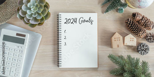 2024 goals new year resolutions on blank note book memo reminder wish list of yearly planner, action plan for work-life balance, good financial health, happy home family, travel aims on office desk photo