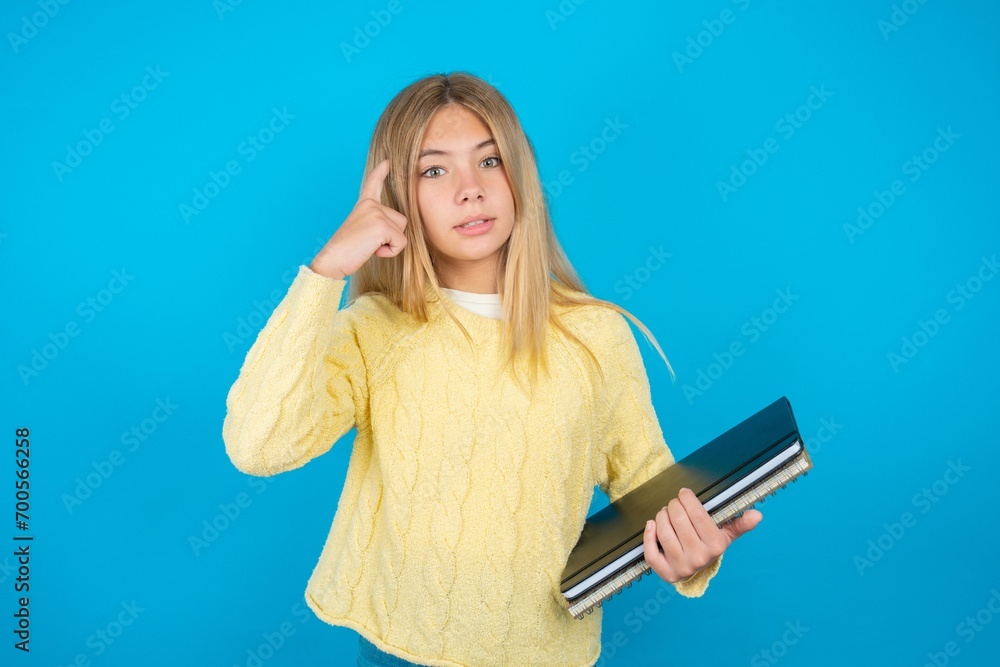 beautiful caucasian teen girl wearing yellow sweater confused and annoyed with open palm showing copy space and pointing finger to forehead. Think about it. beautiful caucasian teen girl wearing yellow sweater confused and annoyed with open palm showing copy space and pointing finger to forehead. Think about it.