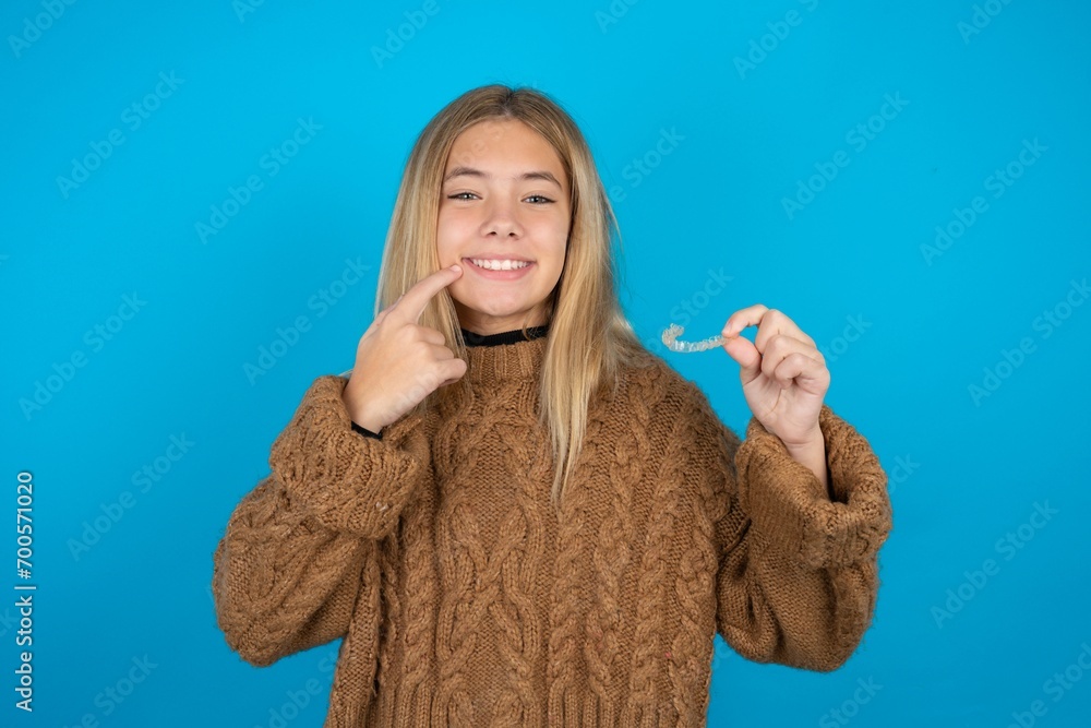 beautiful teen girl holding an invisible aligner and pointing to her perfect straight teeth. Dental healthcare and confidence concept. beautiful teen girl holding an invisible aligner and pointing to her perfect straight teeth. Dental healthcare and confidence concept.
