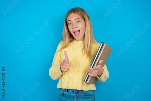 beautiful caucasian teen girl wearing yellow sweater directs fingers at camera selects someone. I recommend you. Best choice