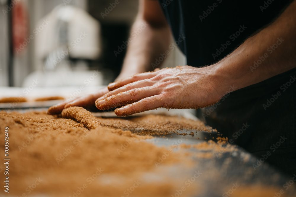 Baker kneading dough on table topped of with cinnamon sugar Baker kneading dough on table topped of with cinnamon sugar