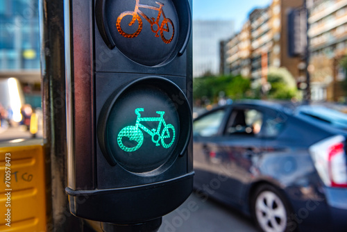 A green cycle lane traffic  signal at a junction in a busy London city street with a car passing in the background. photo
