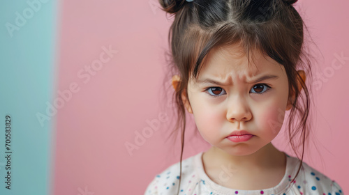 Portrait of sad asian offended crying little girl child on flat color background with copy space, banner template. A sad child makes a grimace.