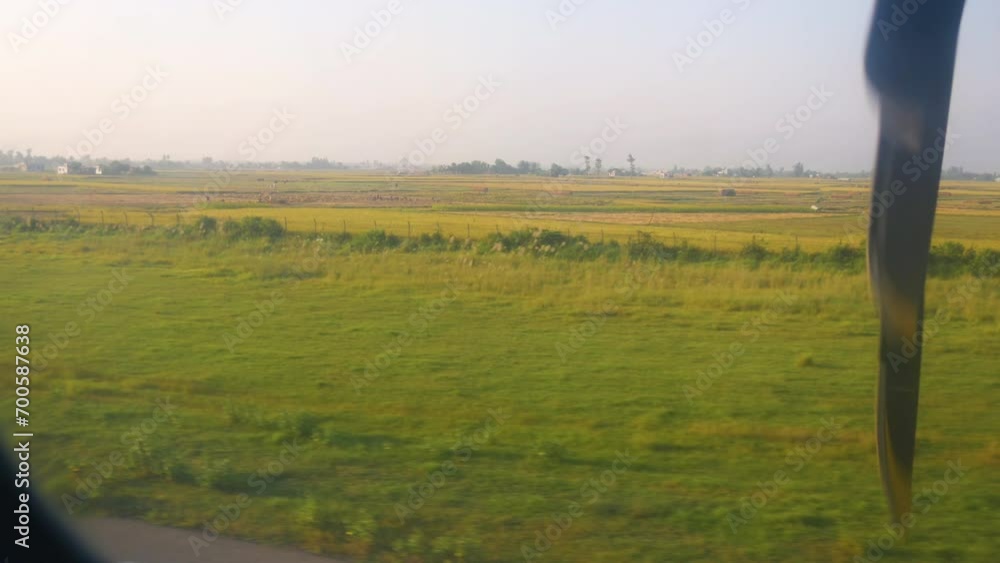 An airplane landing in a rural airport with a view of plain land with crops field emitting beautiful green and yellow texture An airplane landing in a rural airport with a view of plain land with crops field emitting beautiful green and yellow texture