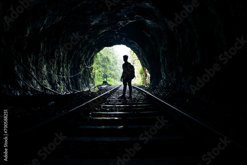 Silhouette of a man standing in a tunnel of rails.