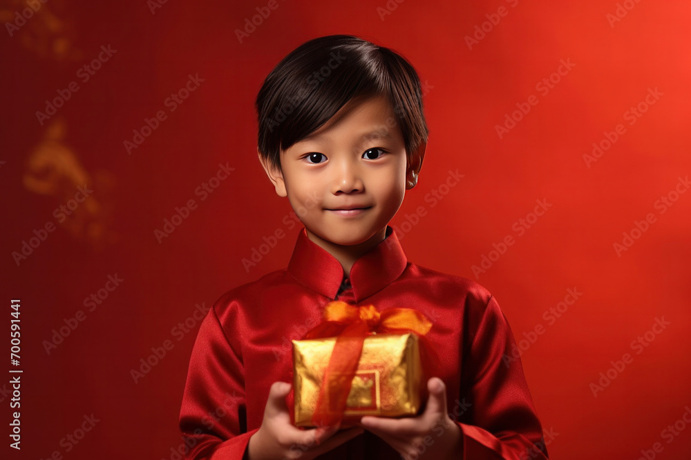 Asian cute boy holding angpao or red packet monetary gift and gold ingot isolated on red background. Happy Chinese new year. Asian cute boy holding angpao or red packet monetary gift and gold ingot isolated on red background. Happy Chinese new year.