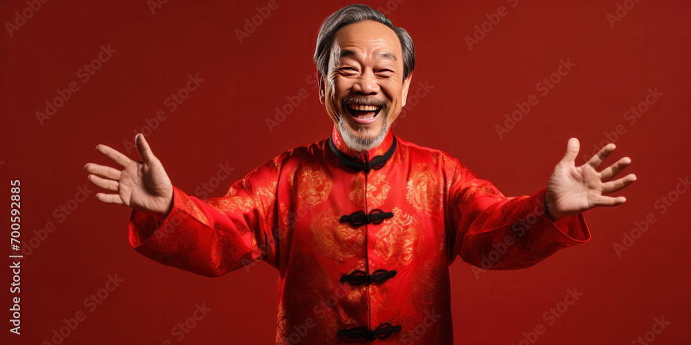 Asian senior man wearing traditional cheongsam qipao dress with gesture of congratulation isolated on red background. Happy Chinese new year.
