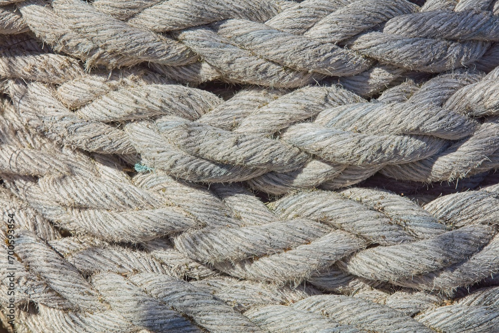 Closeup of tangled pile of old thick ship rope faded in color from use and weather.