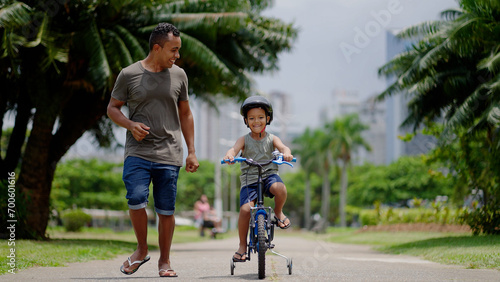 happy spending quality time together outdoors with his son. Kid riding bike having fun with his father
