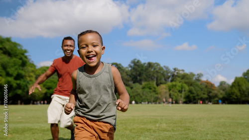 Father and son playing catch-up game outdoors running after each other through city park. Families. Fun, entertainment.

