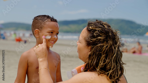 Foto mother applying sunblock lotion on sons skin for sun protection little boy getti