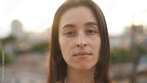 Close up view of white woman looking to camera. Portrait of serious girl standing at sunset light.Concept of people and emotions.

