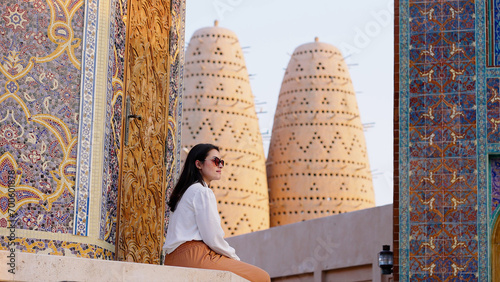 tourist woman sitted at Blue mosque of Katara village made of colorful mosaic in Doha Qatar showing Pigeon tower behind 